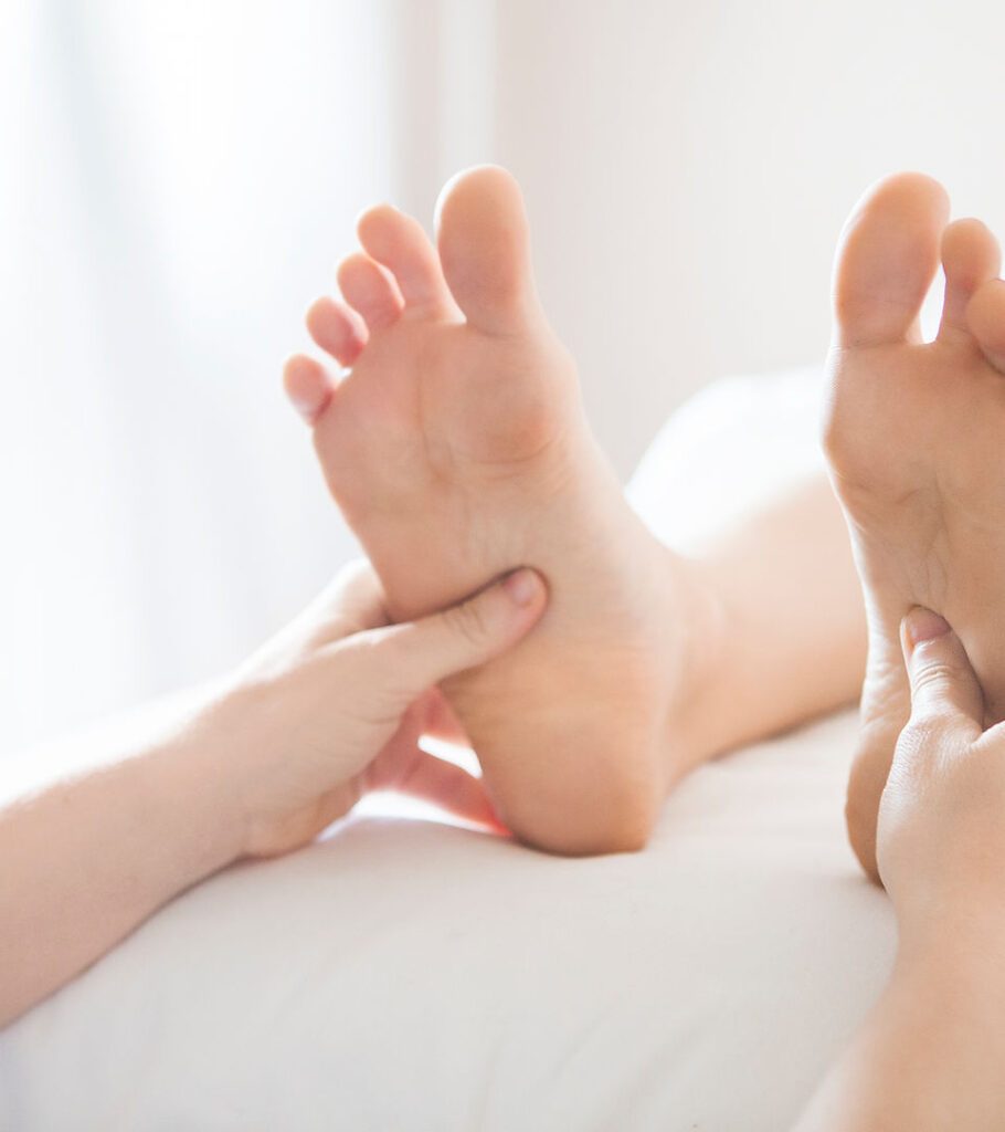 Mains d'un praticien massant délicatement les pieds d'un bébé en soins bien-être